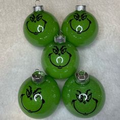 four green christmas ornaments with faces drawn on them