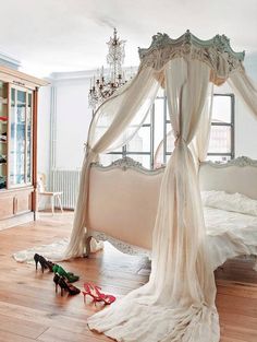 a bedroom with a bed, chandelier and shoes on the floor