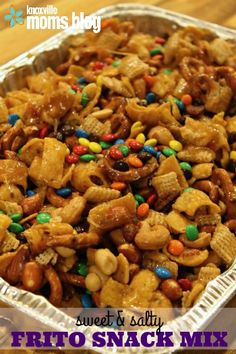 a tin pan filled with snack mix on top of a wooden table