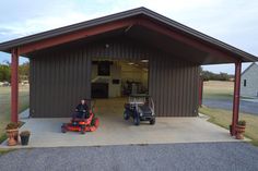 two lawn mowers parked in front of a garage with a man on it