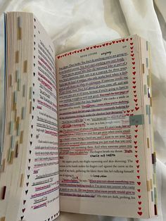 an open book sitting on top of a bed next to a white sheet covered ground