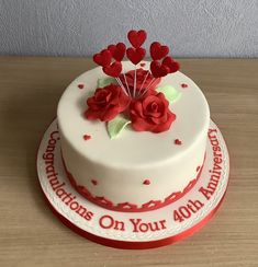 a white cake with red flowers and hearts on the top that reads congratulationss on your 4th anniversary