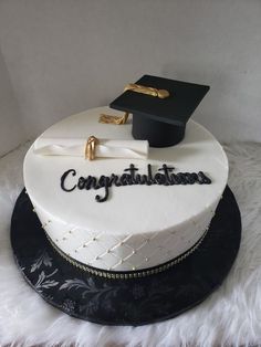 a graduation cake with congratulations written on the side and a mortar cap sitting on top