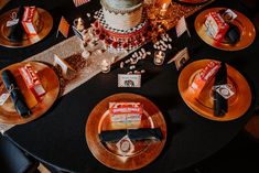 a black table topped with lots of plates and cake