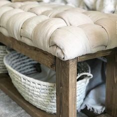 an upholstered bench with baskets underneath it