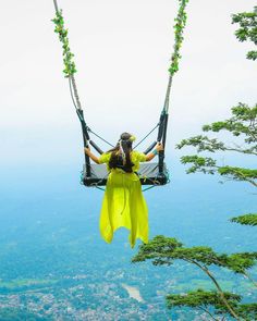 a woman is sitting on a swing in the air