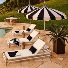 lounge chairs with black and white cushions are next to an outdoor pool