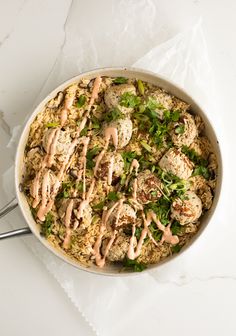 a white bowl filled with rice and meat covered in sauce on top of a table