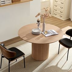 a round table with two chairs and a vase on it in the middle of a room