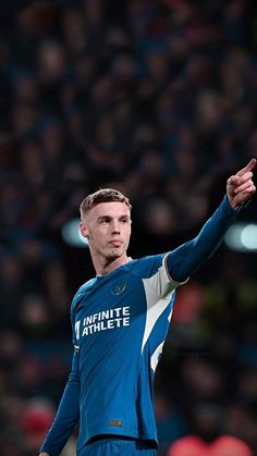 a male soccer player in a blue uniform is holding his hand out to the side