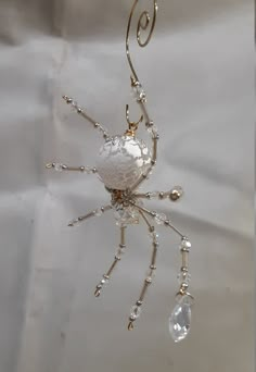 a white spider hanging from a metal hook