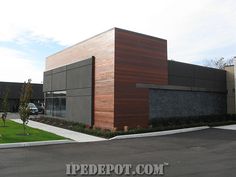 an exterior view of a building with cars parked in the parking lot and grass on the side