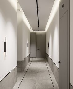 an empty hallway with white walls and black trim on the doors, leading to two elevators