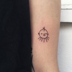 a small tattoo on the arm of a woman's left arm, with an arrow and sun above it