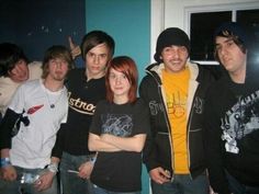 a group of young men standing next to each other in front of a blue wall