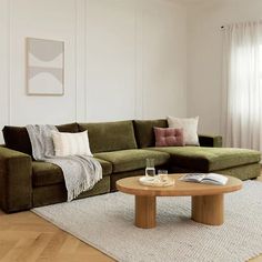 a living room with a green couch and coffee table in front of a white wall