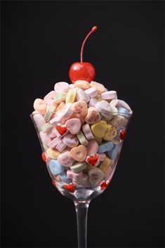 a wine glass filled with candy hearts and a cherry