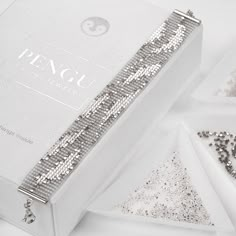 a white box with silver sequins next to other jewelry items on a white surface