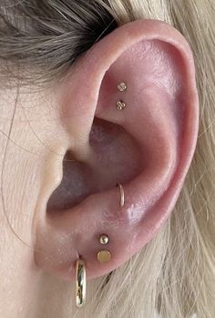 a close up of a person's ear with gold piercings