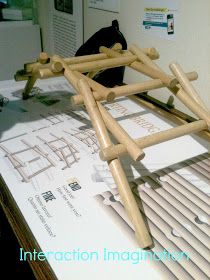 a wooden structure sitting on top of a table next to a black bag and some papers