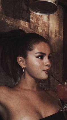 a woman in a black dress drinking from a wine glass with a straw sticking out of her mouth