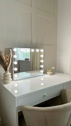 a white vanity with lights on it and a chair