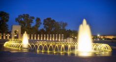 an illuminated fountain in the middle of a park