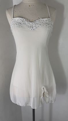 a mannequin wearing a white top with beading on it