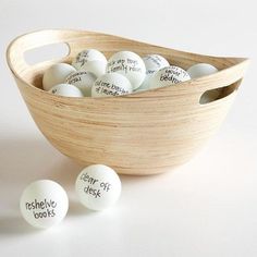 some white eggs in a wooden bowl with writing on them and two small ones next to it