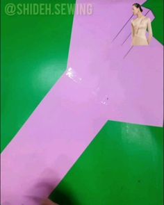 a person is holding up a pink and green paper airplane with a woman on it