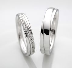 two white gold wedding rings with diamonds on each side, set against a plain background