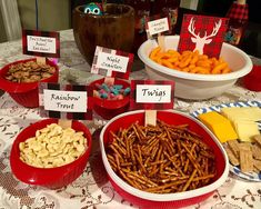 a table topped with red bowls filled with food next to plates of cheese and crackers