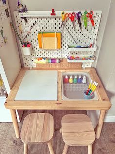 a child's desk with two stools in front of it and pegboard on the wall