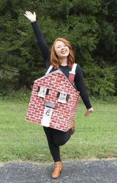 a woman in black shirt holding up a cardboard house