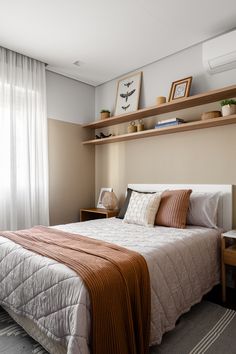 a bed sitting next to a window in a room with white curtains and wooden shelves