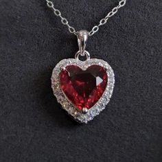 Make a bold statement with this stunning red heart pendant necklace, beautifully crafted in sterling silver. The vibrant heart-shaped red stone is surrounded by a halo of sparkling white stones, creating a dazzling effect that is sure to catch the eye. This necklace is perfect for adding a touch of romance and elegance to any outfit. The pendant is paired with a 45+5 cm adjustable silver chain, making it a versatile piece that can be worn for both casual and formal occasions. Its rich red color Red Stone Pendant, Honeymoon Looks, Red Heart Pendant Necklace, Ruby Heart Necklace, Red Heart Pendant, Red Heart Necklace, Ruby Heart, Chain Making, White Stones