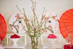 there are three vases with flowers in them and two red umbrellas on the wall