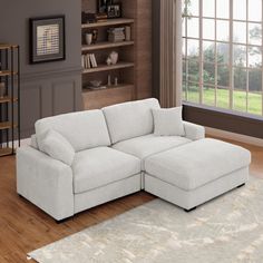 a living room with a large white sectional couch and bookcase on the wall next to it