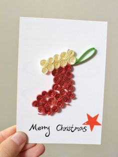 a hand holding up a christmas card made out of rolled paper