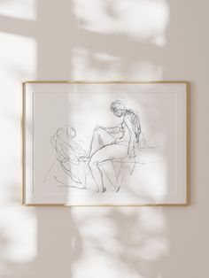 a drawing is hanging on the wall next to a framed photo with shadow from it