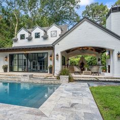 a house with a swimming pool in front of it and an outdoor dining area on the other side