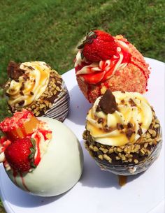 four cupcakes on a white plate with strawberries