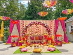 an outdoor wedding setup with umbrellas and flowers on the stage, decorated in bright colors