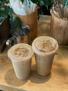 two iced coffees sitting on top of a wooden table