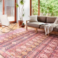 a living room area with a couch, chair and rug on the floor in front of large windows