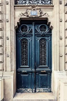 an old building with two blue doors and ornate iron work on the front door,