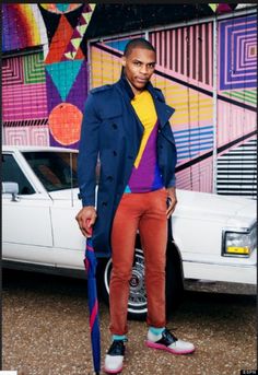 a man standing in front of a white car wearing colorful socks and an overcoat