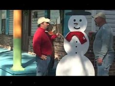 two men standing next to a snowman on the side of a building with another man looking at it