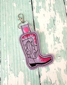 Cowboy Boot Keychain, Cowboy Boot Key chain, Boot Zipper Pull, Cowboy Boot Gift, Cowboy Boot Bag Tag, Key Fob --- 70 Colors These cowboy boot keychains are a cute accessory for any fan.  These are perfect for keys, bag tags or zipper pulls.  Choose your vinyl color and thread color from the drop down box below, these are shown with hot pink thread on lavender glitter vinyl.  This will come on a swivel clasp.  This measures 1.5" wide and 3.5" tall, including the split ring.  It's made from two layers of vinyl and a KAM snap keeps the swivel clasp attached. Cowboy Boot Keychain, Boot Keychain, Pink Thread, Cowboy Boot, Bag Tag, Glitter Vinyl, Boot Bag, Zipper Pulls, Split Ring