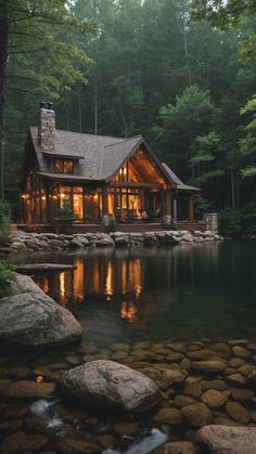 a house sitting on top of a lush green forest next to a body of water